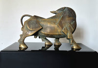 A bronze bull sculpture with geometric details, displayed on a glossy black pedestal . Backside close upImage. 