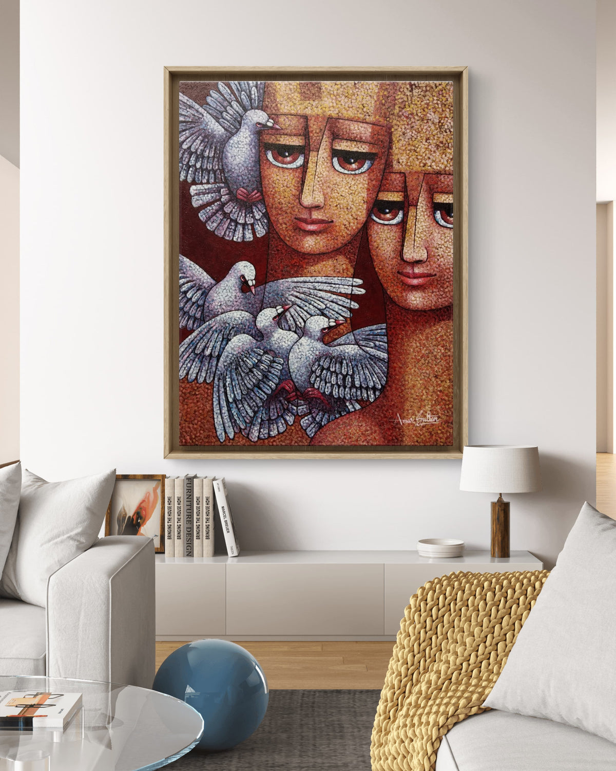 Framed artwork with two faces and doves in a living room setting. 