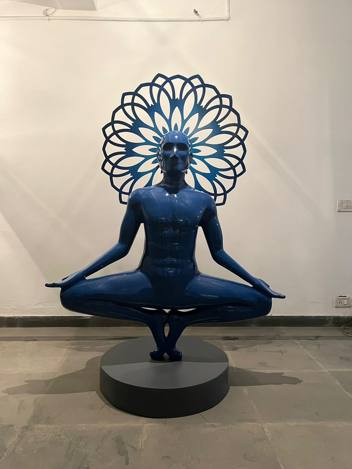 Front View of the 6ft Vernika Singh  sculpture; man in yoga posture with halo behind him. 