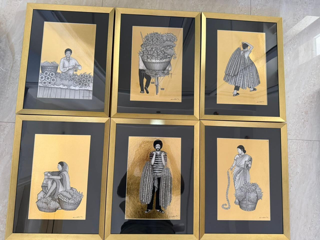 Six framed Kapil Anant artworks featuring scenes from Indian flower market. Each Artwork  features a black and white illustration on gold foil.