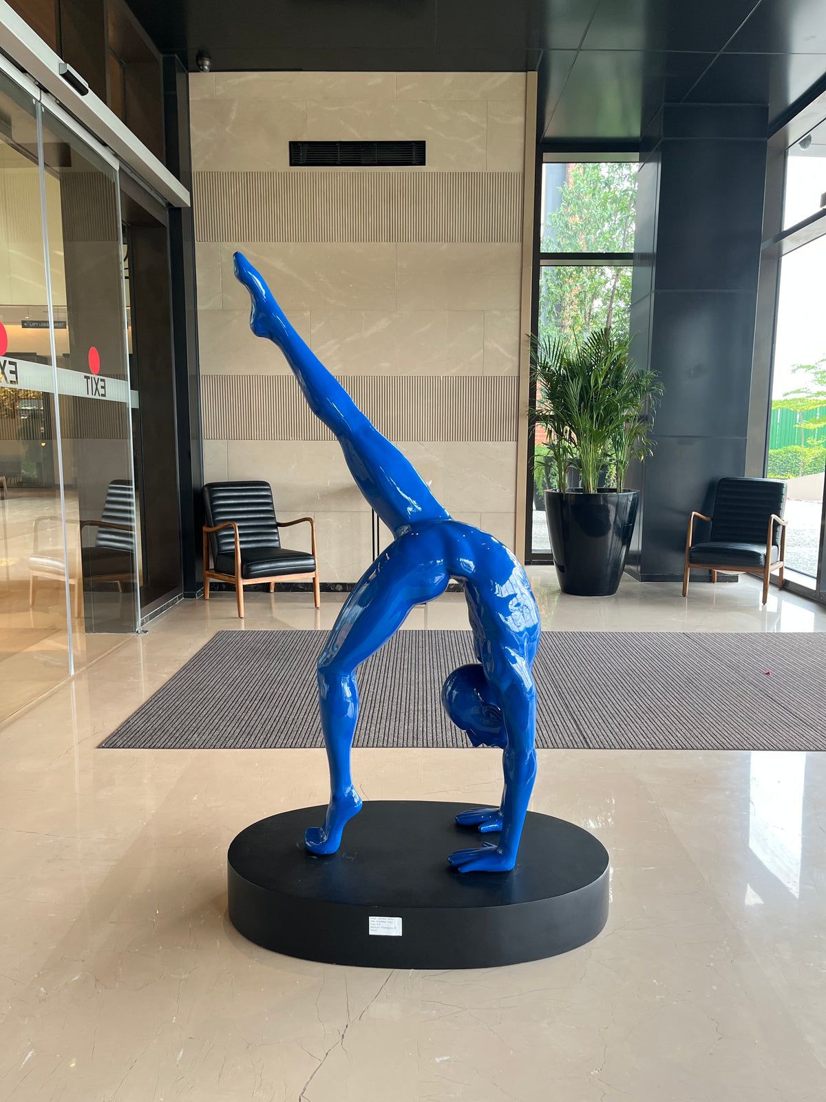 Blue Fiberglass sculpture of a person in a handstand on a black base. 
