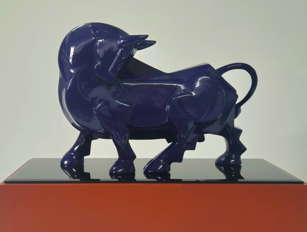Dinkar Jadhav navy blue glossy fiberglass bull sculpture; matte red wooden base. 