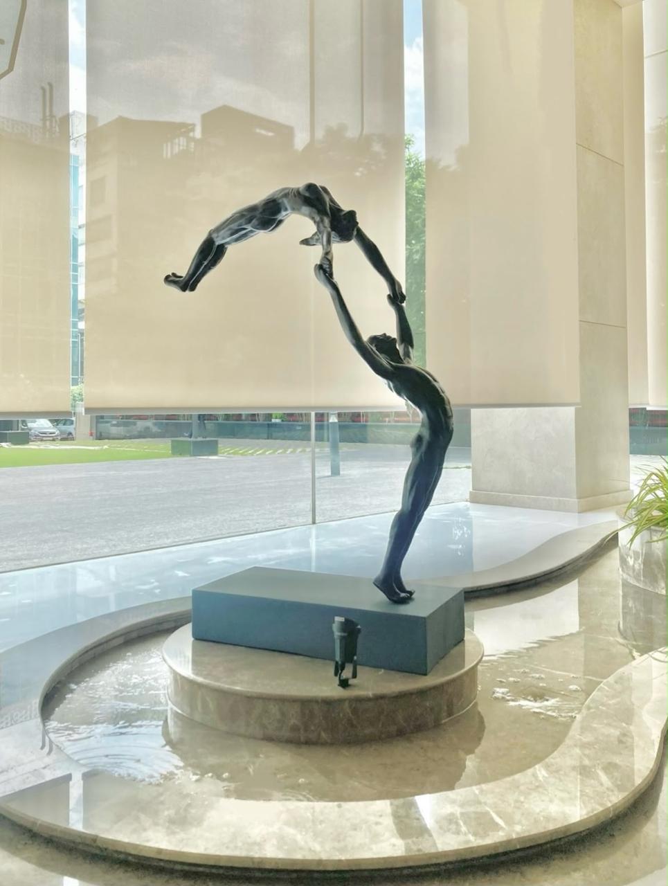 Vernika Singh's tall fiberglass gymnasts couple sculpture. A man flips a female gymnast in air. 