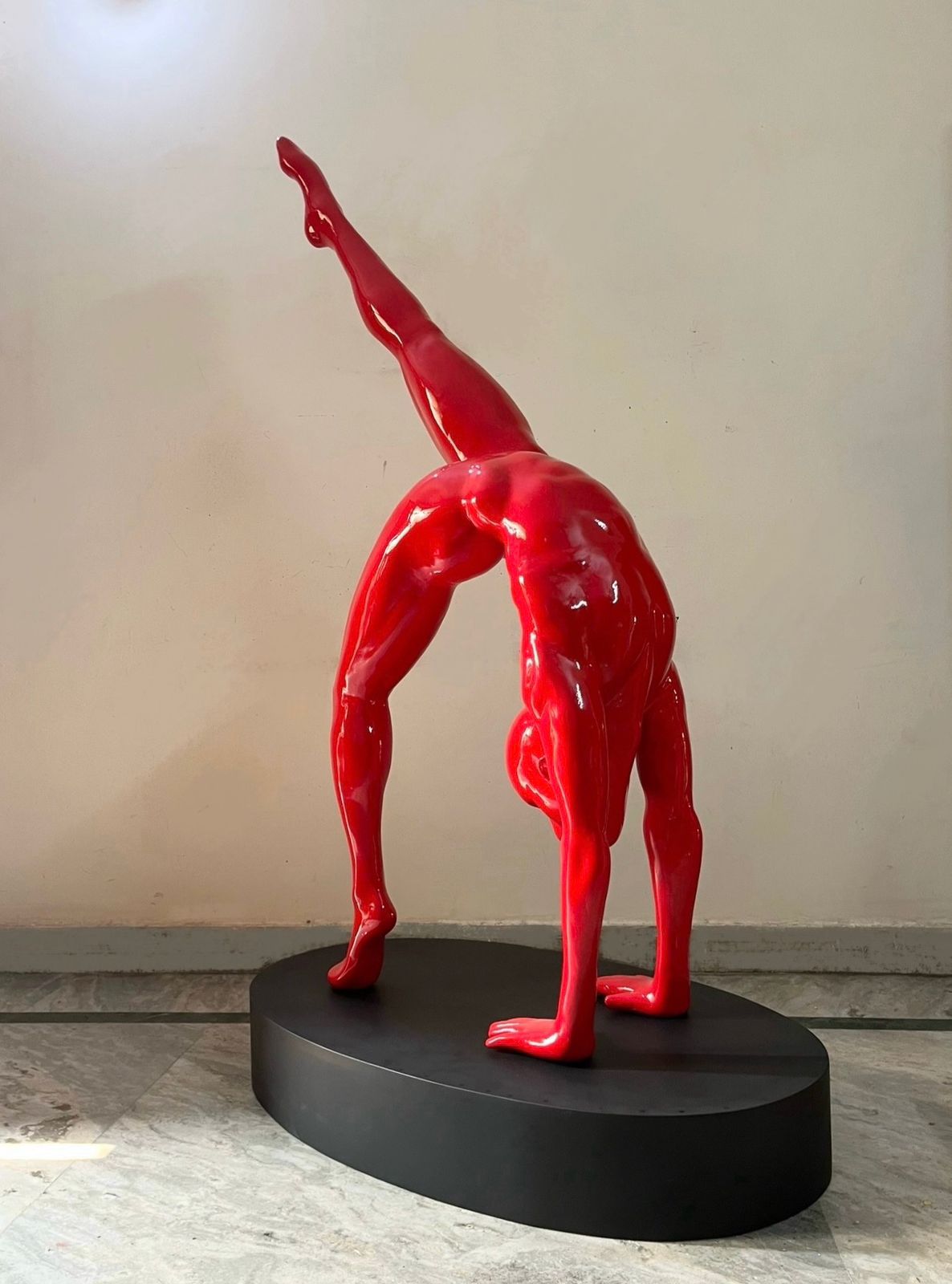 A glossy red sculpture of a human figure doing yoga by Vernika SIngh. Side Image