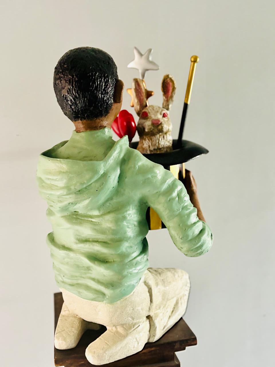 Statue of a child in a green shirt with a rabbit and star popping of magic hat. 