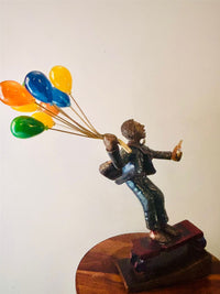 Statue of a man in corporate holding colorfull balloons riding a skateboard.